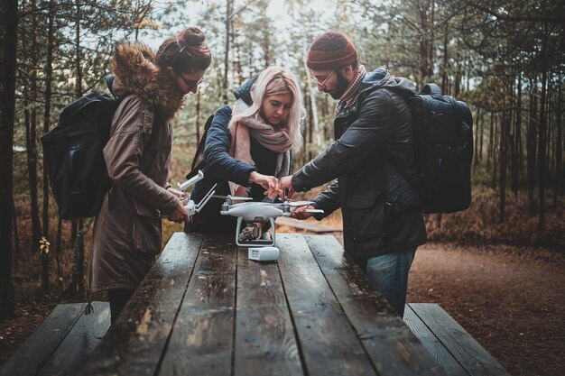 Un pequeño grupo de amigos está montando drones en el parque forestal usando una mesa de madera.