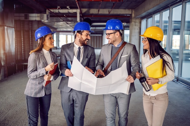 Pequeno grupo de arquitetos dedicados e altamente motivados caminhando pelo prédio, eles querem renovar e falar sobre novas ideias para corrigir projetos.