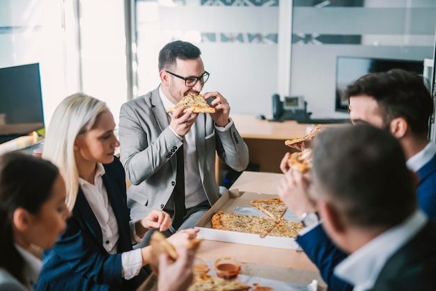 Un pequeño grupo de empresarios hambrientos almorzando en la sala de juntas