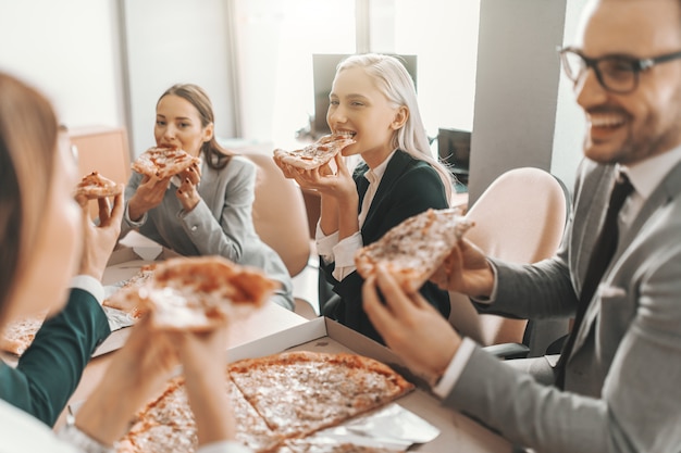 Pequeño grupo de empresarios en trajes almorzando juntos. Enfoque selectivo en mujer rubia. Lo bueno del trabajo en equipo es que siempre tienes a otros de tu lado.