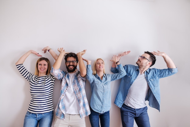 Pequeño grupo de personas levantando las manos en el aire como si estuvieran sosteniendo algo. Poner en marcha el concepto de negocio.