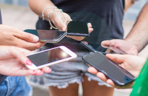 Pequeño grupo de personas que usan teléfonos celulares juntos