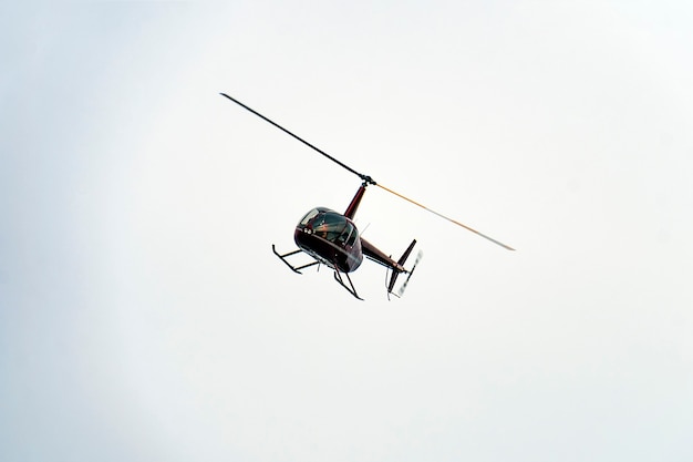 Un pequeño helicóptero rojo volando en el cielo.