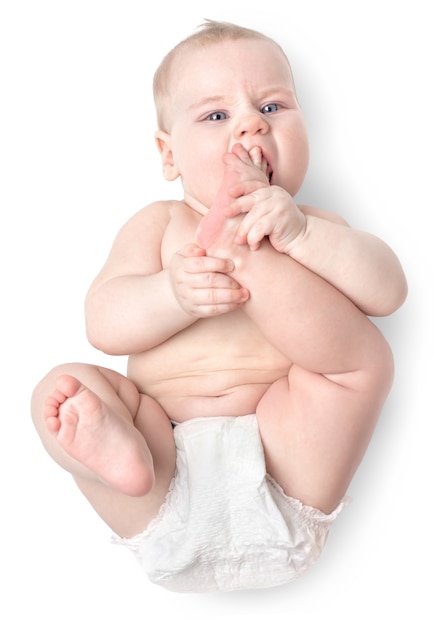 El pequeño y hermoso niño caucásico se acuesta de espaldas y lame un pie. aislado en blanco