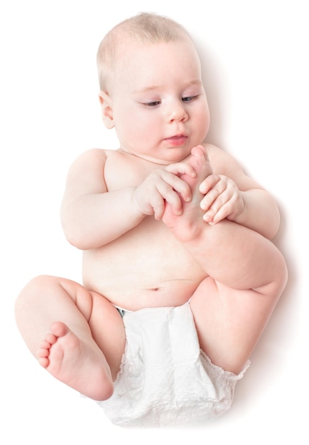 El pequeño y hermoso niño caucásico se acuesta de espaldas y lame un pie. aislado en blanco