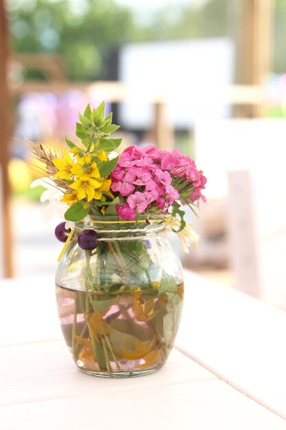 Foto un pequeño y hermoso ramo de flores de verano en un jarrón sobre una mesa composición