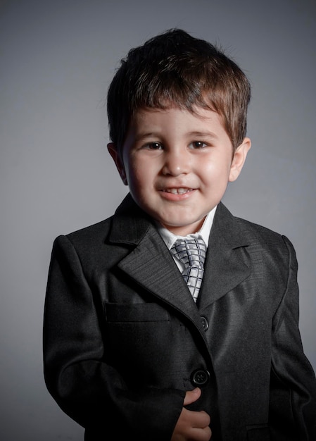 pequeño hombre de negocios, niño de cabello castaño vestido con traje y corbata con caras y expresiones divertidas
