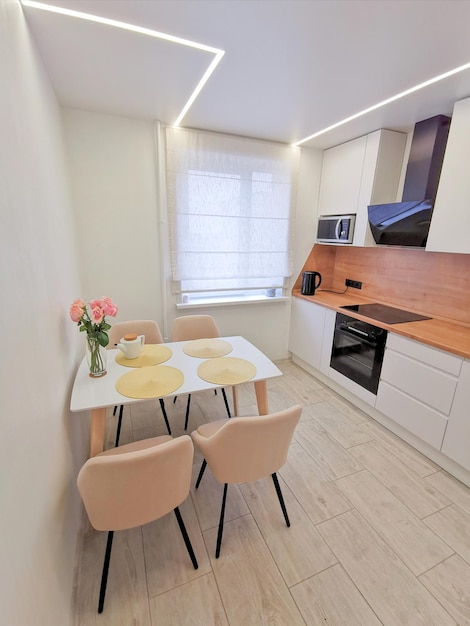 Pequeño interior de cocina blanca. Apartamento minimalista moderno en blanco con elementos negros y de madera.