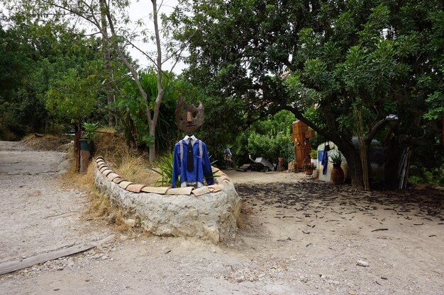 Un pequeño jardín con una estatua de un hombre vestido con una camisa azul y un sombrero.