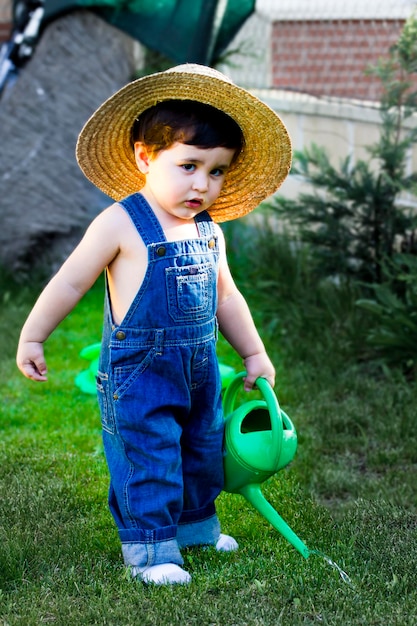 pequeno jardineiro bebê concentrado em seu trabalho regando as plantas