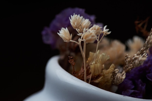 Un pequeño jarrón blanco con una flor dentro.