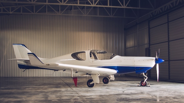 Foto pequeño jet privado blanco estacionado en el hangar