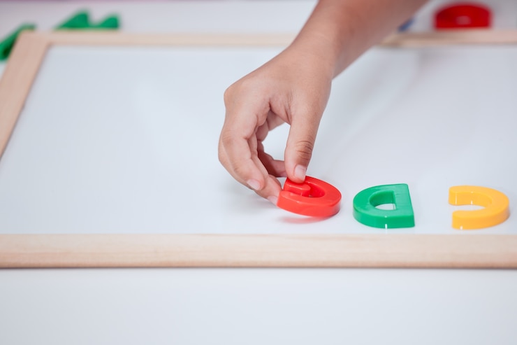 Foto pequeño juego de la mano de niña niño y aprender alfabetos magnéticos a bordo