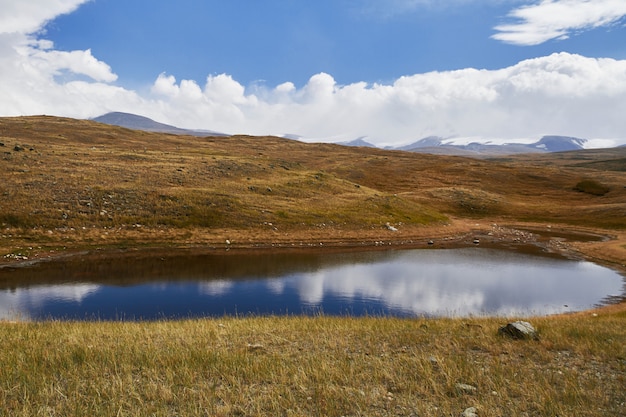 Un pequeño lago en la estepa, cae entre las montañas. La meseta de Ukok en el Altai. Fabulosos paisajes fríos