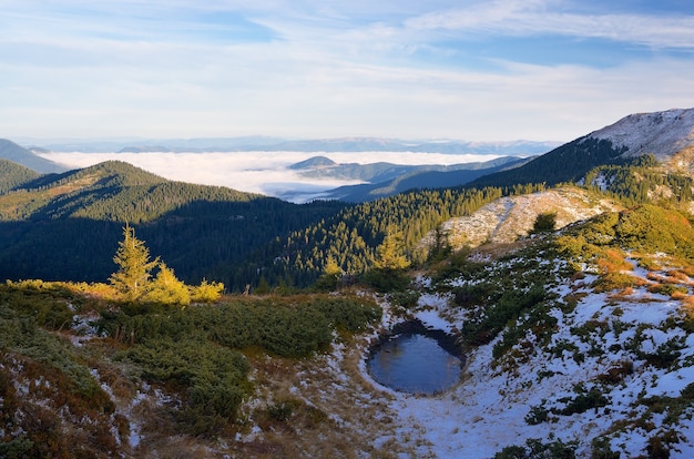 Pequeño lago de montaña en la ladera. Paisaje otoñal con la primera nevada. Cárpatos, Ucrania, Europa