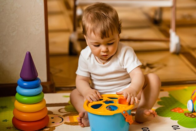 Foto pequeño y lindo bebé jugando con coloridos juguetes educativos en la alfombra de juegos en el interior de la casa