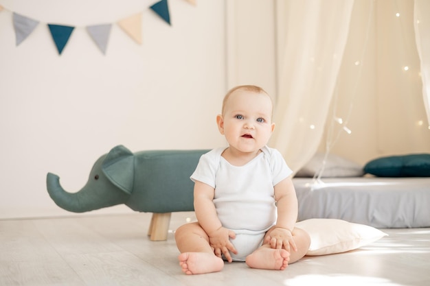 Pequeño y lindo bebé en una luminosa habitación infantil con un wigwam jugando con un mono de algodón y sonriendo