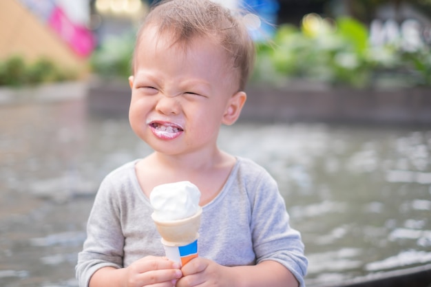 Foto pequeño y lindo niño asiático sonriente de 1 año bebé niño comiendo helado suave