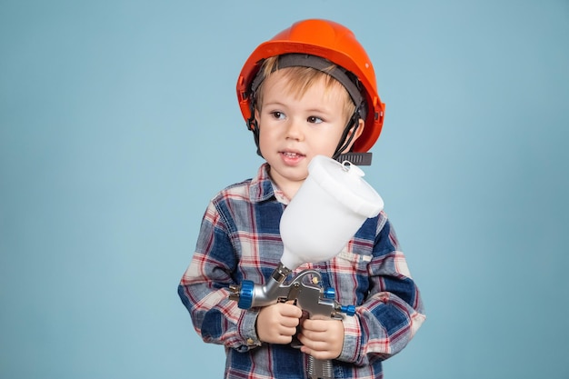 Pequeño y lindo niño caucásico con casco con pistola eléctrica