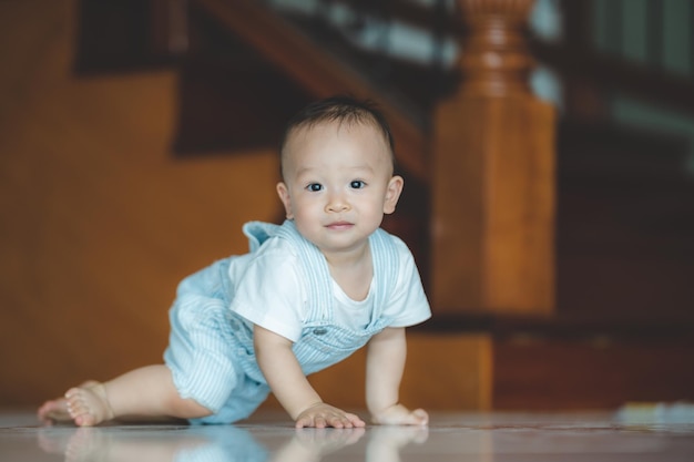 Pequeño y lindo niño intentando y aprendiendo a gatear en casa