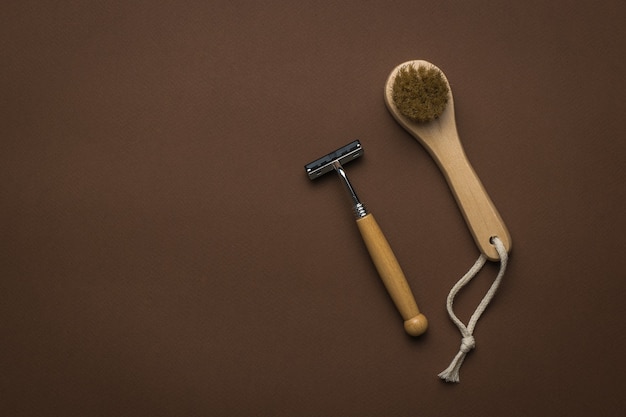 Un pequeño masajeador facial de mano y una navaja con mango de madera sobre un fondo marrón. Endecha plana. Lugar para el texto.