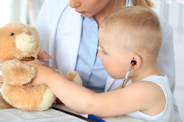 Pequeno médico examinando um paciente de urso de brinquedo por estetoscópio