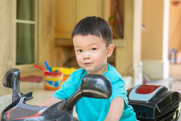 Pequeno, menino asiático, bicicleta equitação, brinquedo, inthe, casa, com, feliz, rosto