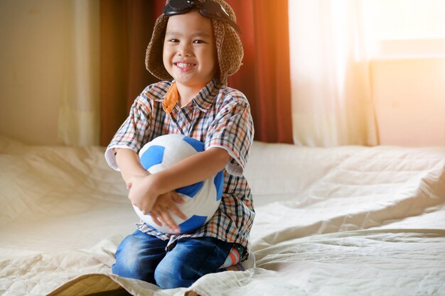 Pequeno menino asiático brincando com bola, conceito de viagem e aventura
