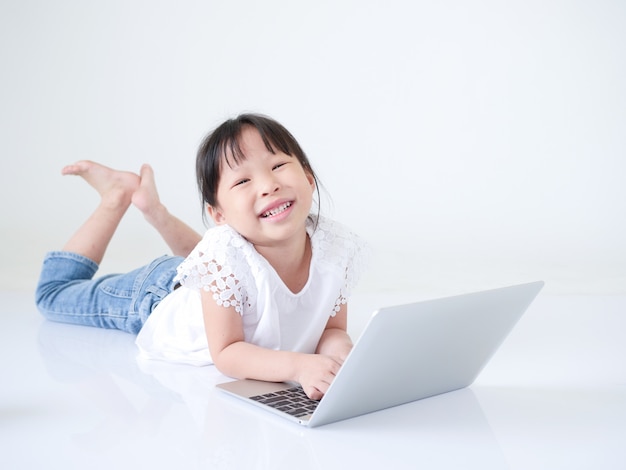 Pequeño mensaje asiático de la muchacha que mecanografía en la computadora portátil sobre el fondo blanco.