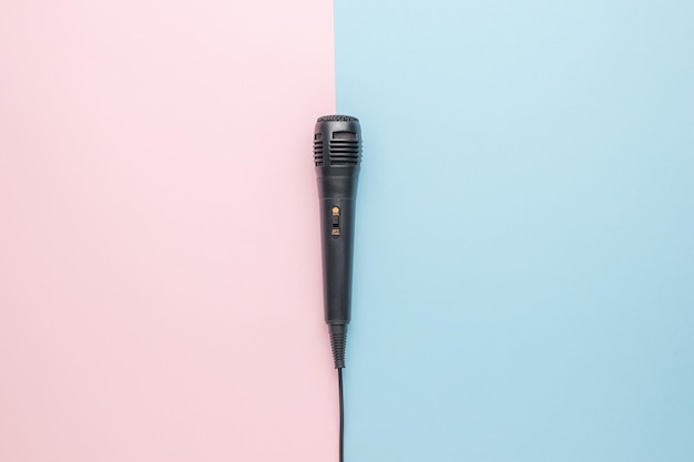 Un pequeño micrófono con cable negro sobre un fondo rosa y azul El concepto de grabación de sonido y música