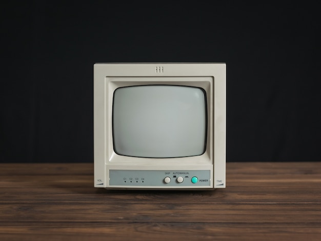 Foto pequeno monitor retro em uma mesa de madeira em um fundo preto. equipamento de videovigilância antigo.