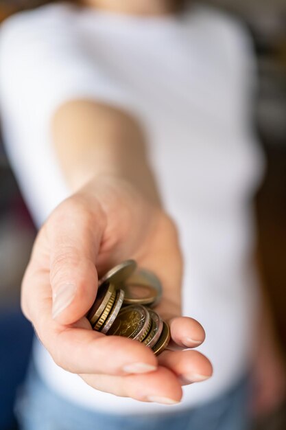 Pequeño montón de monedas en una mano femenina sobre un fondo borroso Concepto de crisis y ahorro de dinero