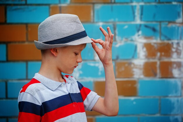 El pequeño muchacho elegante en un sombrero del verano se coloca en día de verano.