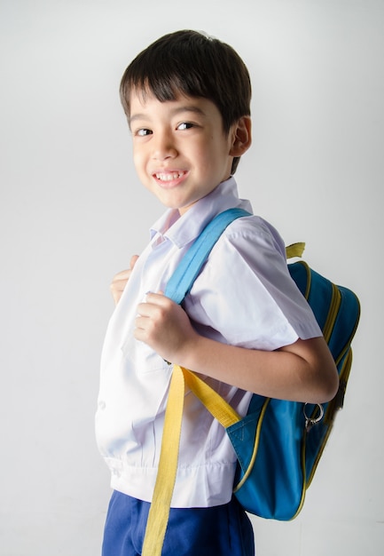 Pequeño muchacho estudiante en uniforme sobre fondo blanco.