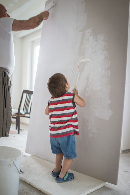 Foto pequeño muchacho lindo que pinta en una pared