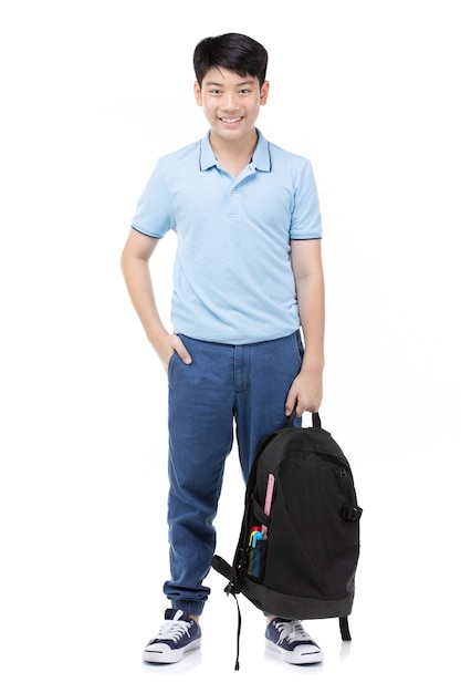 Pequeño muchacho sonriente del estudiante en camiseta azul del polo adentro con los libros y el bolso.