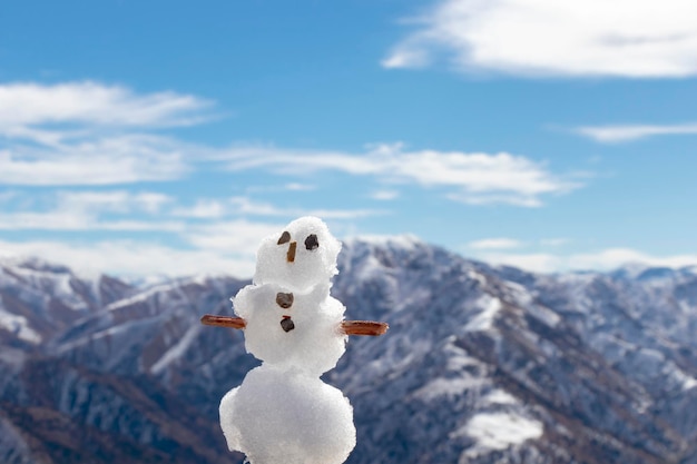 Un pequeño muñeco de nieve en el fondo de montañas nevadas