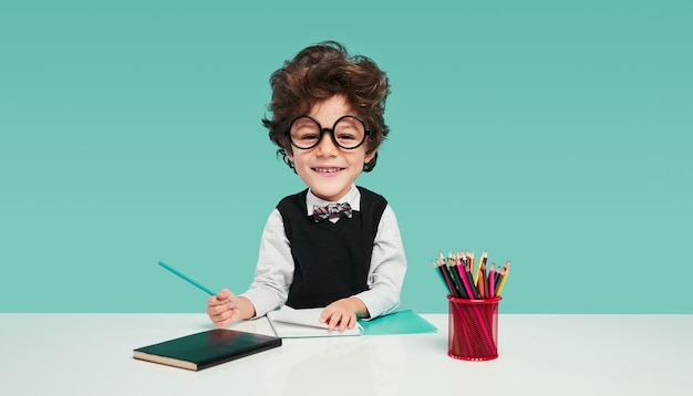 Pequeno nerd fazendo lição de casa com sorriso