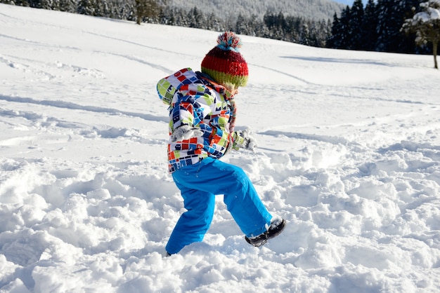 Pequeño niño de 3 años jugando en la nieve.