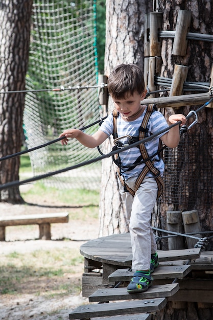 Pequeño niño activo que juega en red que sube. Los niños juegan y escalan al aire libre en un día soleado de verano.