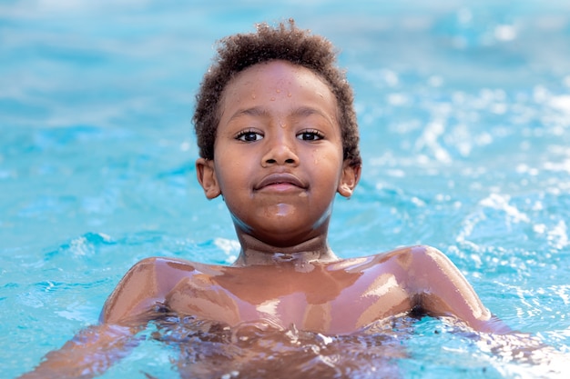 Pequeño niño africano chapoteando en la piscina