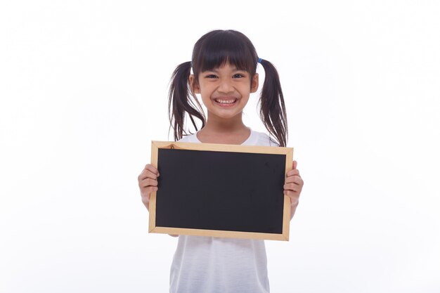 Pequeño niño asiático muestra el tablero negro en la pared