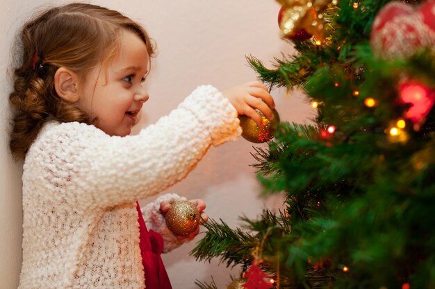 Pequeño niño hermoso cerca del árbol de navidad.