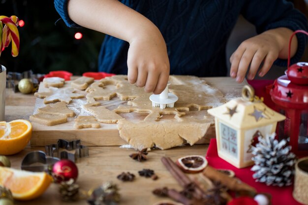 El pequeño niño lindo hace galletas de jengibre de Navidad en la cocina de Año Nuevo.