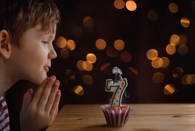 Pequeño niño lindo que sopla velas en las tortas de cumpleaños.