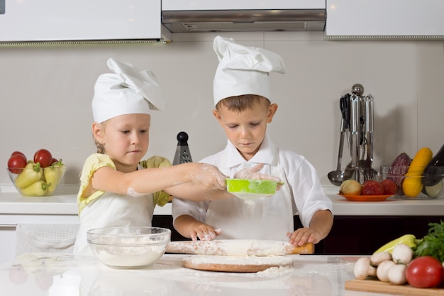 Pequeño niño y niña horneando juntos en la cocina