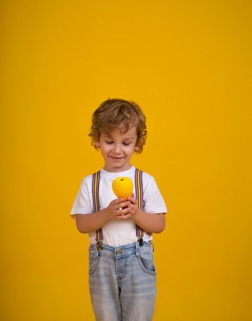 Foto un pequeño niño de pelo rizado sobre un fondo amarillo