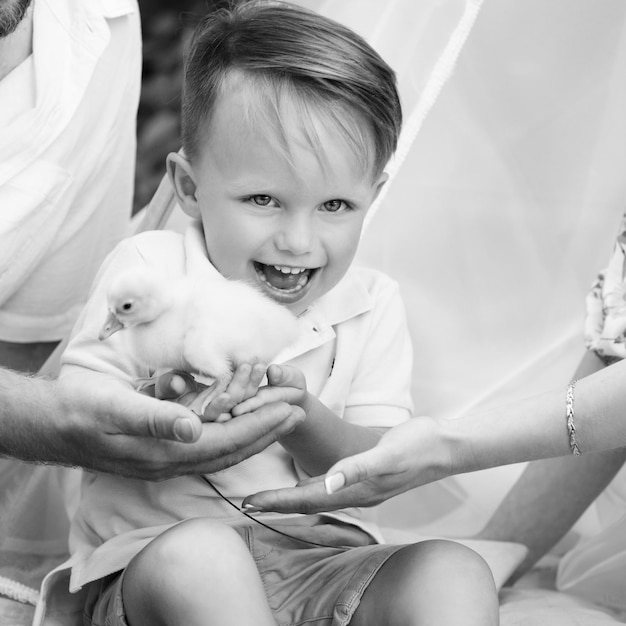 El pequeño niño sonriente con patitos yace en una hierba en el verano