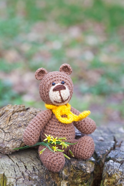 Un pequeño oso pardo con una bufanda amarilla. Juguete de punto, hecho a mano, amigurumi.