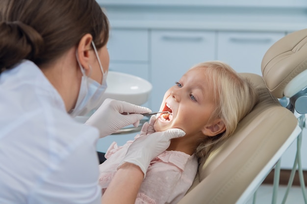 Un pequeño paciente abre la boca para un chequeo dental